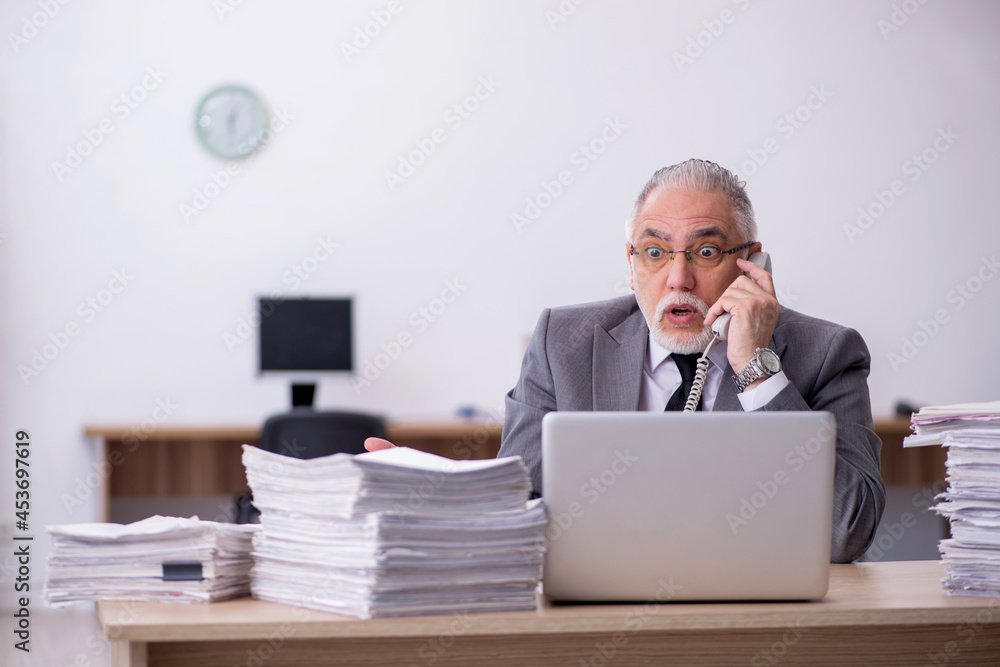 Old male employee unhappy with excessive work in the office Old male employee unhappy with excessive work in the office