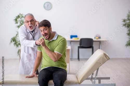 Young man visiting old male doctor