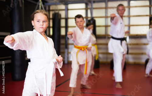 Girl fighting karate stand in the gym. Children in a pair practice karate