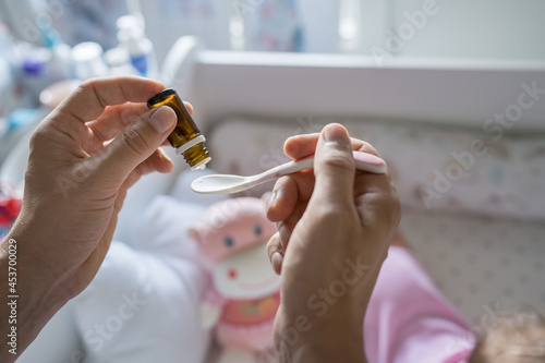 Tableau sur toile Father preparing spoon with probiotic drops medicine for his small caucasian bab