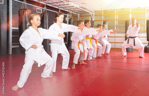 Children wearing karate uniform practicing new moves in group at gym