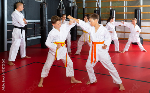 Two preteen boys working in pair, mastering new karate moves in class