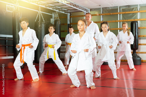 Group of kids practicing taekwondo and warming up for training while standing barefoot