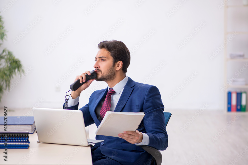 Young male employee sitting at workplace Young male employee sitting at workplace