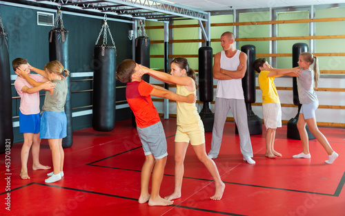Young children working in pair mastering new self-defense moves at gym © JackF