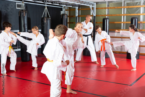 Adolescent boys and girls in kimono fighting with each other in gym.