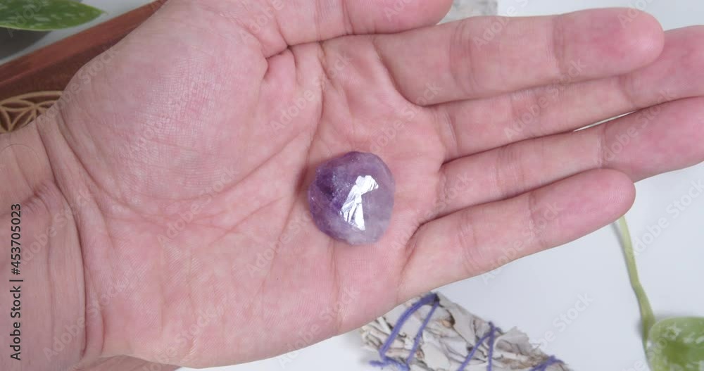 Amethyst tumbled stone in the palm of a hand Amethyst tumbled stone in the palm of a hand