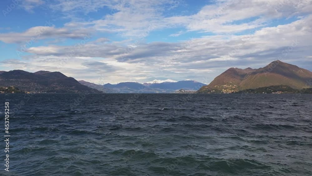 Slow-motion and zoom-out of waves over Maggiore lake water with Alps mountain range in background, Stresa in Italy Slow-motion and zoom-out of waves over Maggiore lake water with Alps mountain range in background, Stresa in Italy