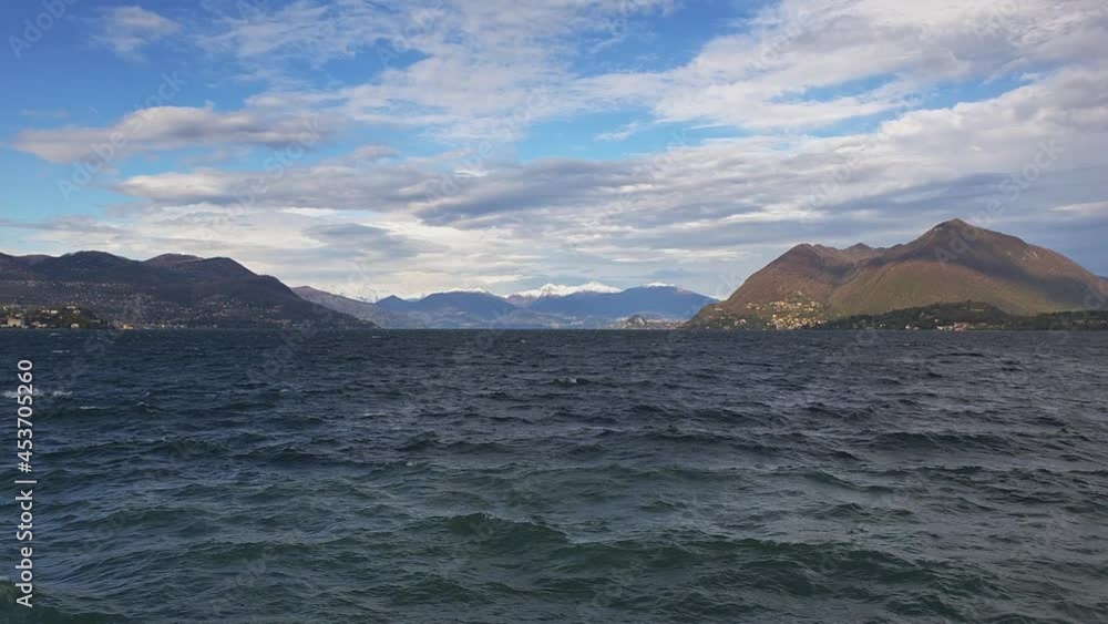 Real-time of waves over Maggiore lake water with Alps mountain range in background, Stresa in Italy Real-time of waves over Maggiore lake water with Alps mountain range in background, Stresa in Italy
