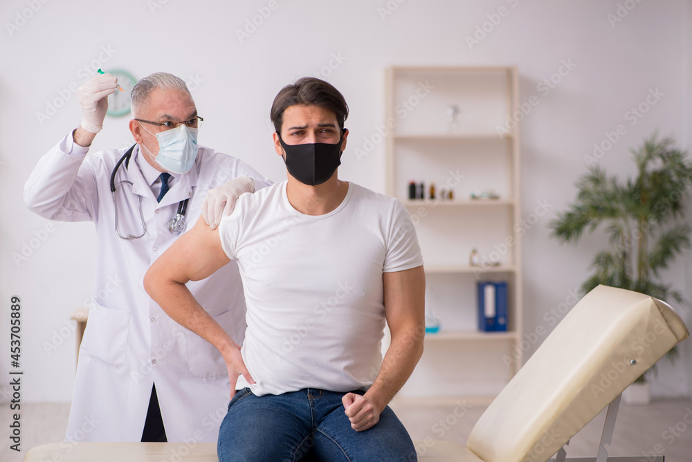 Obraz premium Young male patient visiting old doctor in vaccination concept