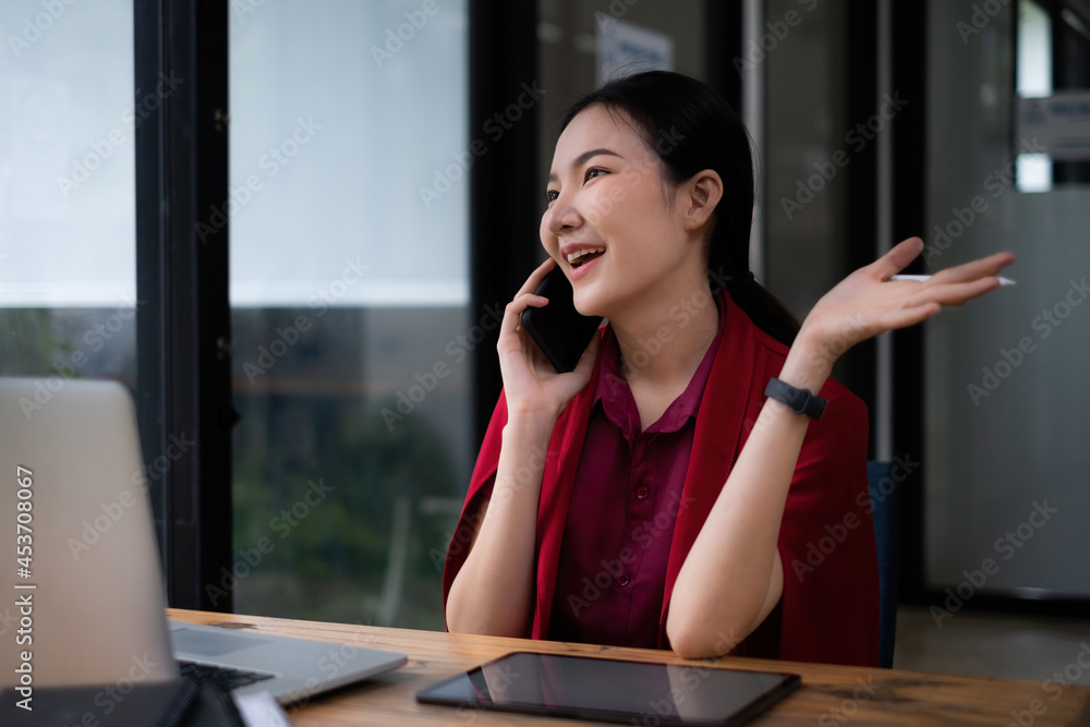 Photo of gorgeous secretary talking with customer by cell phone at office. she sitting at the wooden desk. Photo of gorgeous secretary talking with customer by cell phone at office. she sitting at the wooden desk.