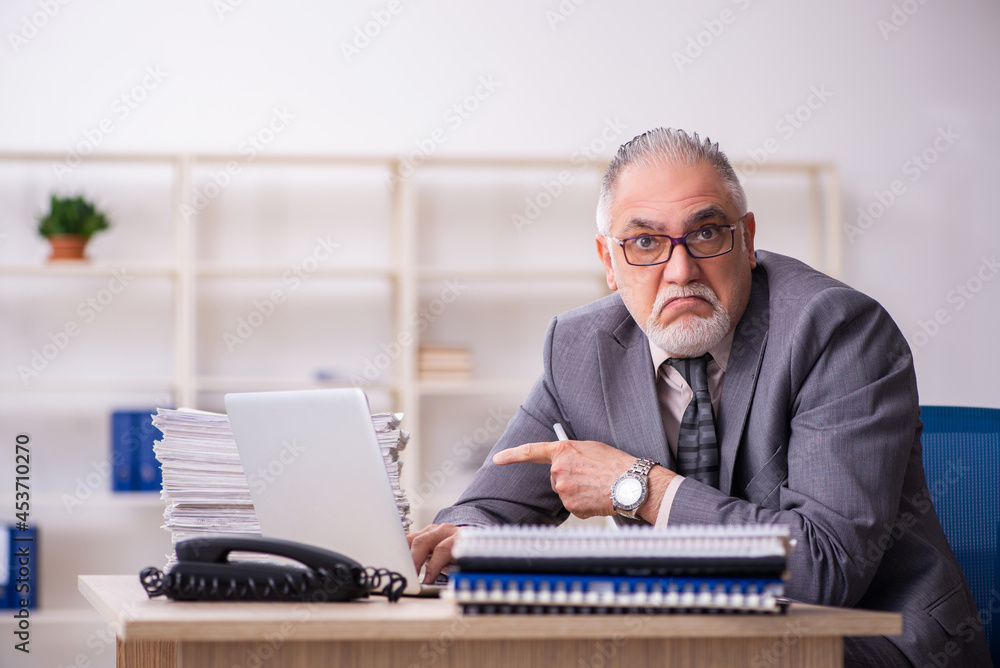 Old male employee working at workplace Old male employee working at workplace