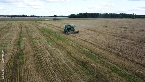 Aerial view of a green vintage combine harvester mows wheat in the field for the food industry, yellow reap grain crops, sunny summer day, dolly shot moving right photo