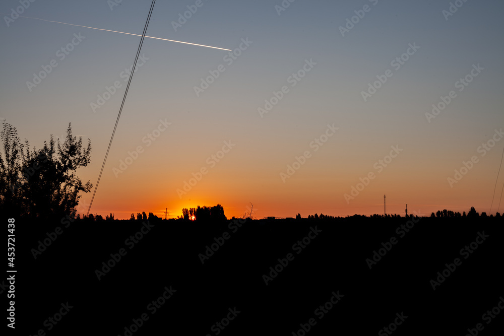 Naklejka premium trail of a flying plane in the morning sky at dawn