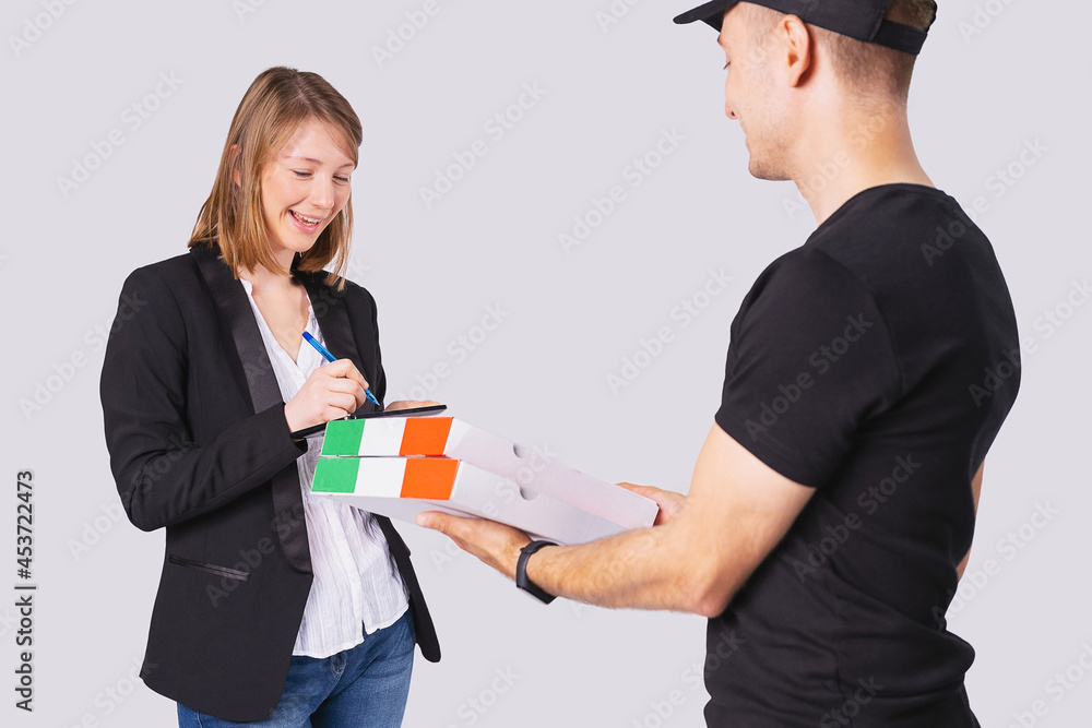 Post man in black uniform delivered pizza to a beautiful blonde business woman with happy face expression and she holding the pen in her hand to sign for the delivery. Post man in black uniform delivered pizza to a beautiful blonde business woman with happy face expression and she holding the pen in her hand to sign for the delivery.