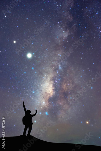 Milky Way on Night sky and silhouette man on the mountain, Success or winner, leader concept. High iso with Noise.