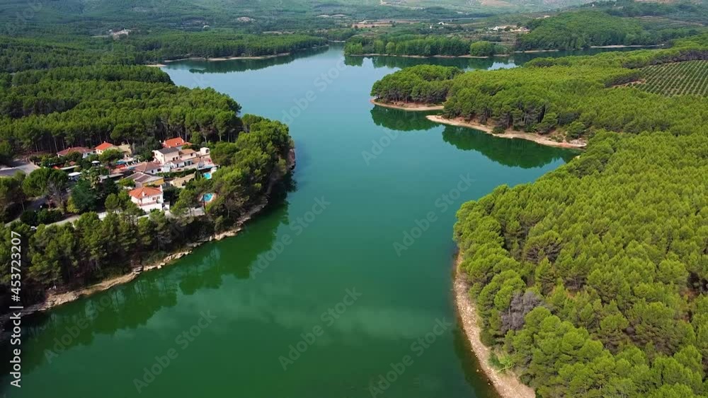 Calm Waters Of Ulldecona Dam With Dense Forest And Houses In Castellon, Spain. aerial Calm Waters Of Ulldecona Dam With Dense Forest And Houses In Castellon, Spain. aerial