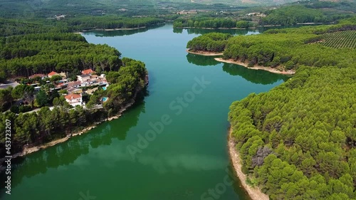 Calm Waters Of Ulldecona Dam With Dense Forest And Houses In Castellon, Spain. aerial photo