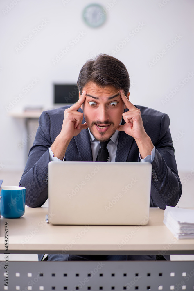 Young male employee sitting at workplace Young male employee sitting at workplace