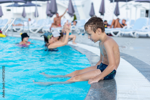 Fototapeta Naklejka Na Ścianę i Meble -  The boy on the side of the pool is smiling. The open air swimming pool.