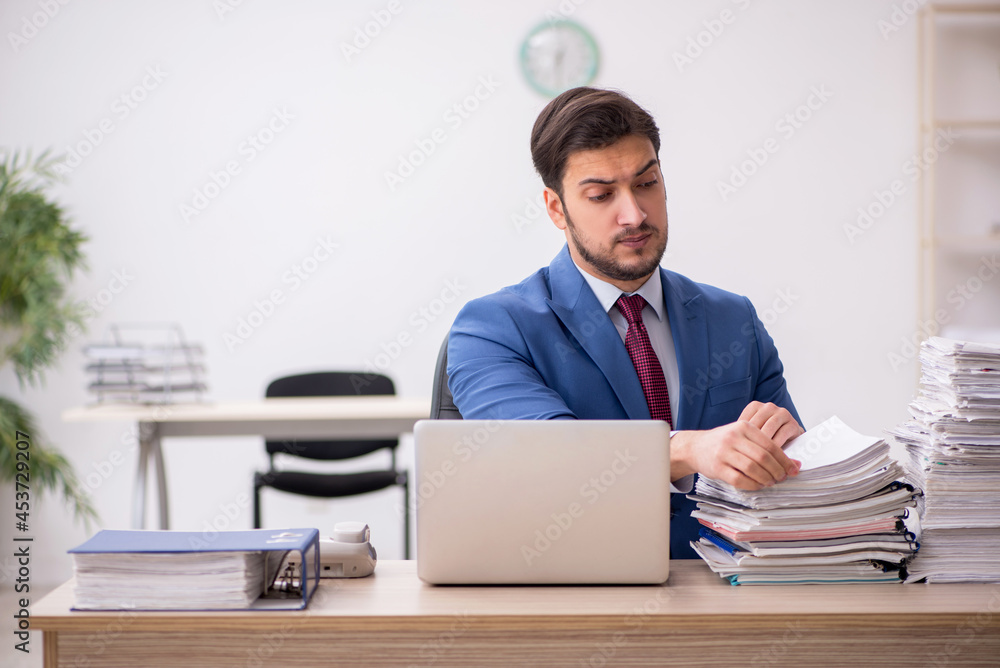 Young male employee and too much work in the office Young male employee and too much work in the office