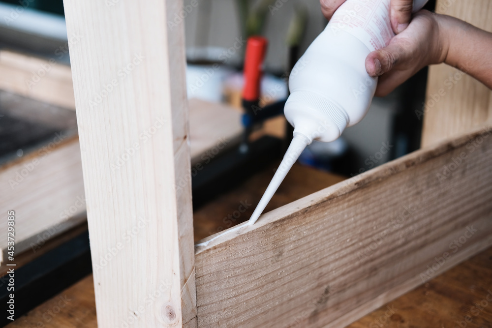 Woodworking operators are using glue to put together the wood parts to assemble and build a wooden table for their customers. Woodworking operators are using glue to put together the wood parts to assemble and build a wooden table for their customers.
