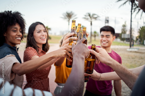 Close-up of hands of a group of young people of different races toasting happily at sunset. Cheers.
