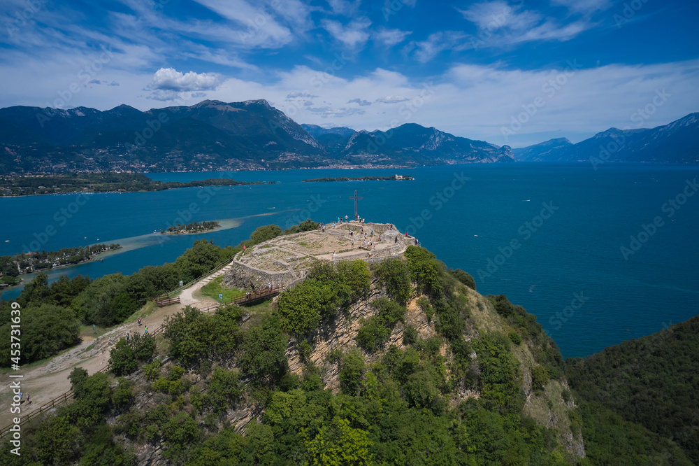 Lake Garda, Italy aerial view. Fortress with a cross on a hill in the background Lake Garda. Fortress Rocca di Manerba aerial view. Panorama on the rocca di manerba top view.