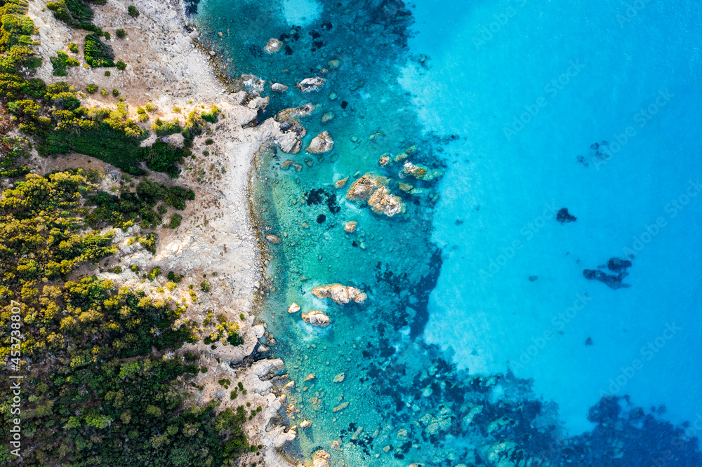 Obraz premium View from above, stunning aerial view of a green and rocky coastline bathed by a turquoise, crystal clear water.Sardinia, Italy.