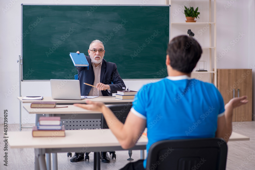 Old male teacher and young male student in front of blackboard Old male teacher and young male student in front of blackboard