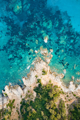 View from above, stunning aerial view of a green and rocky coastline bathed by a turquoise, crystal clear water. Costa Smeralda, Sardinia, Italy.