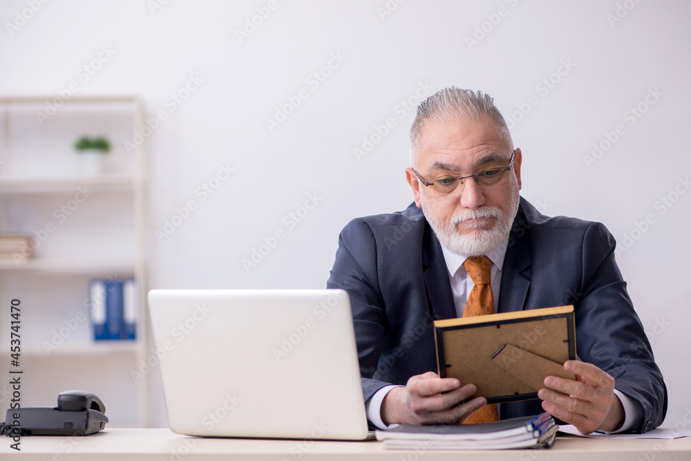 Old male employee missing his wife at workplace