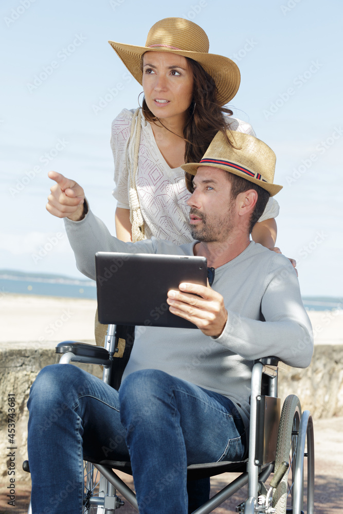 man in a wheelchair shows something on his tablet
