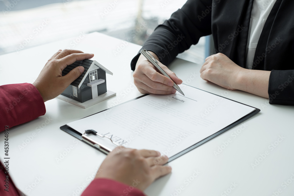 A real estate agent with a House model is talking to clients about buying home insurance. Real estate Home insurance concept A real estate agent with a House model is talking to clients about buying home insurance. Real estate Home insurance concept