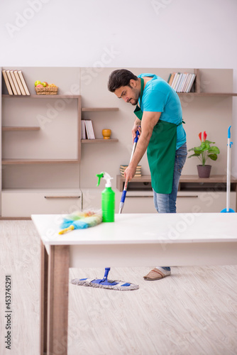 Young male contractor cleaning the house