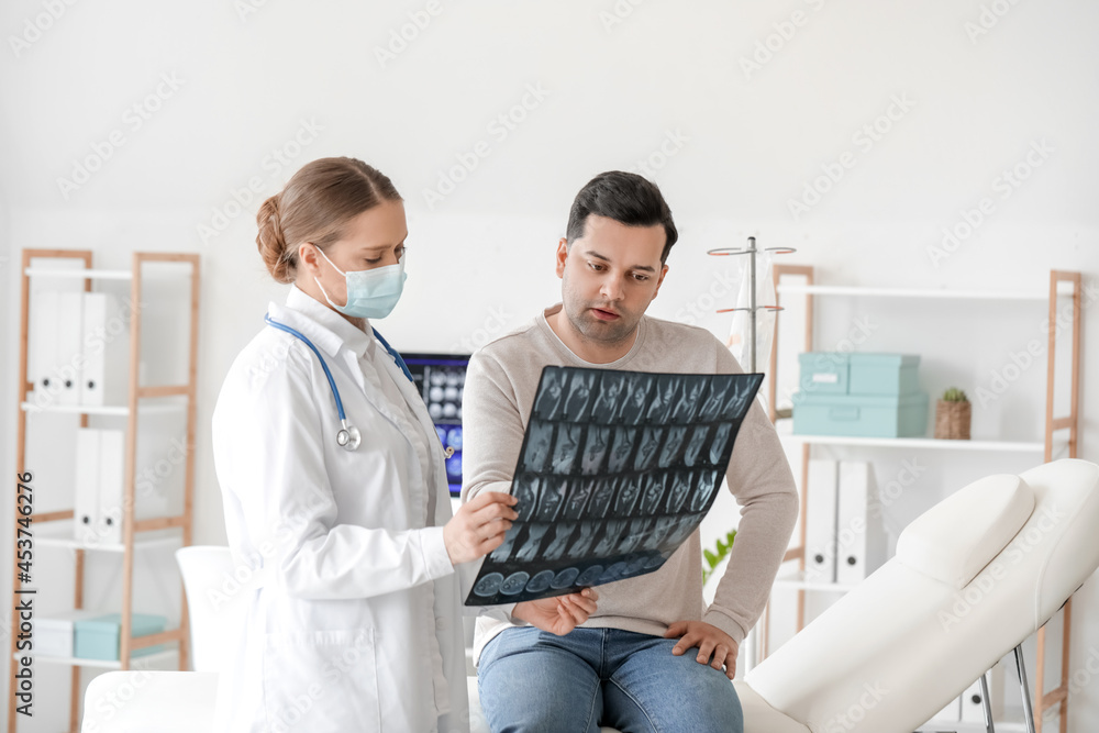 Female doctor showing x-ray scan to patient in clinic Female doctor showing x-ray scan to patient in clinic