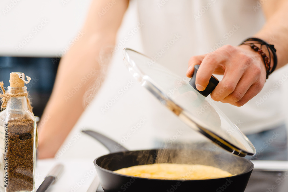 Young white man using frying pan while cooking in kitchen