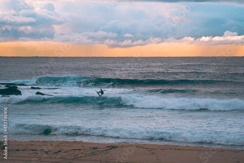 silhouette of surfer at the beach catching waves at sunset