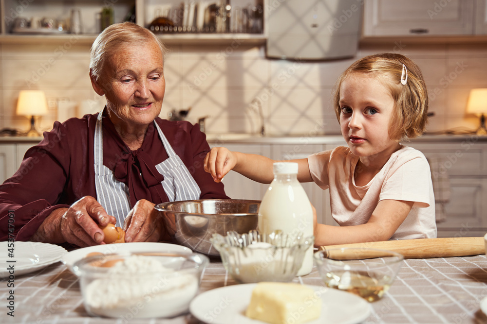Girl adding salt to dish under granny supervision