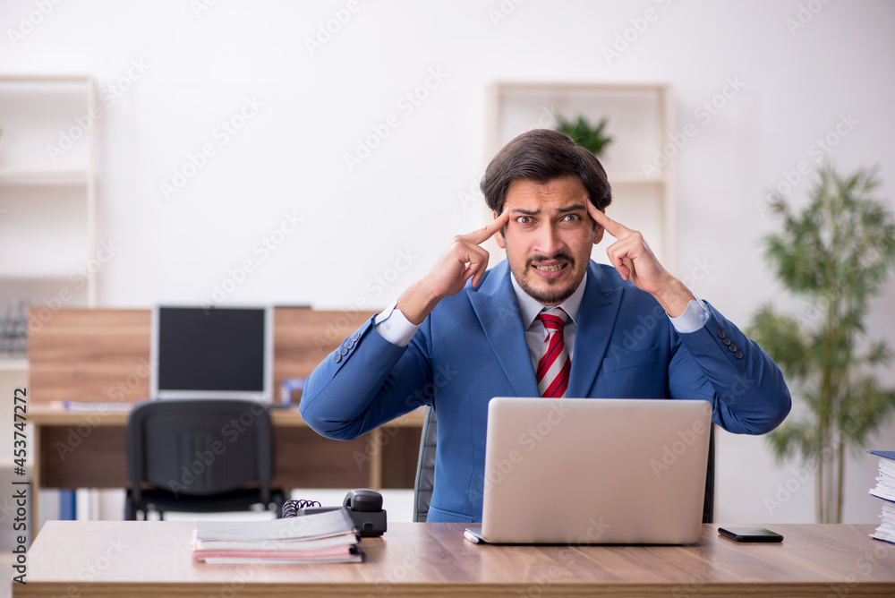 Young male employee sitting at workplace Young male employee sitting at workplace