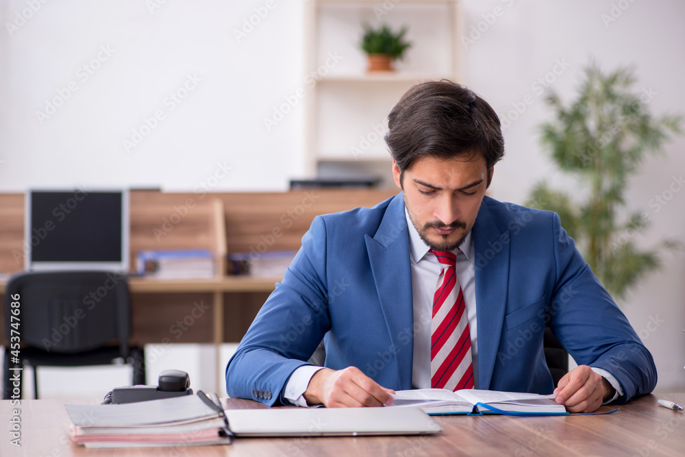 Young male employee sitting at workplace