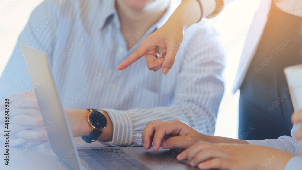 Business people discussing meeting. Businesswoman pointing with finger on laptop computer. Close-up young business hand.