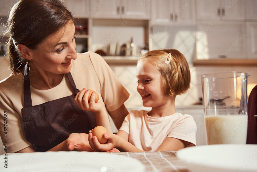 Girl choosing between two eggs with her mother Girl choosing between two eggs with her mother