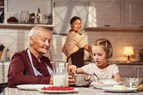 Focused girl mixing ingredients in bowl with her granny