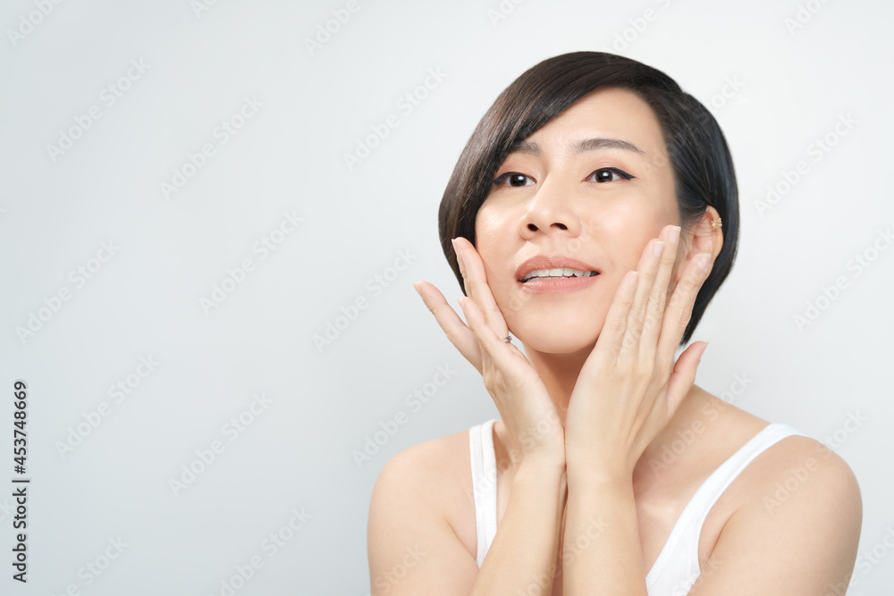 Glowing skin treatment. Portrait of a beautiful asian woman with flawless facial in white inner wear gently touching her cheeks with hands. K-beauty, Collagen, Skincare, Products, V shape, 40s, 30s. Glowing skin treatment. Portrait of a beautiful asian woman with flawless facial in white inner wear gently touching her cheeks with hands. K-beauty, Collagen, Skincare, Products, V shape, 40s, 30s.