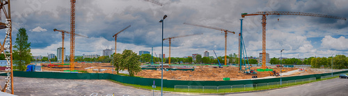 View of New Mass Construction Site with Macines and Cranes Against Sky with Clouds. photo