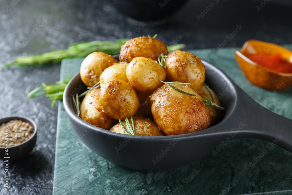 Frying pan with baked potatoes and rosemary on dark background Frying pan with baked potatoes and rosemary on dark background
