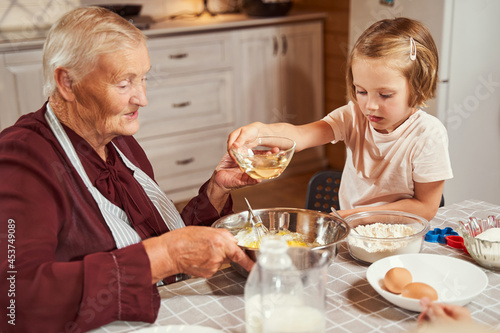 Girl passing a glass bowl with liquid to grandmother