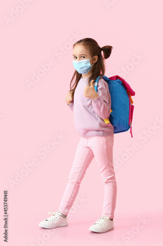 Little schoolgirl in medical mask on color background © Pixel-Shot