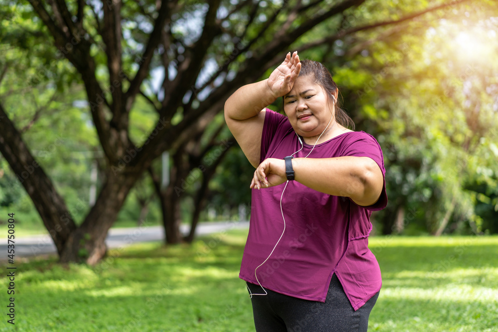 Fat woman asian checking time or heart rate from smart watch. Exercise outdoors for weight loss idea concept With Fat woman asian checking time or heart rate from smart watch. Exercise outdoors for weight loss idea concept With